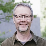 A headshot of Tim Wright a director at COMET, and SatSense Ltd, standing outside in a leafy courtyard