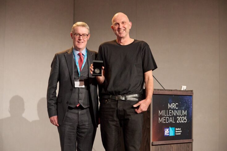 Professor Patrick Chinnery awarding the 2025 MRC Millennium Medal to Professor George Davey Smith on stage at the award ceremony