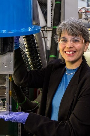 A woman wearing safety glasses standing in front of a machine