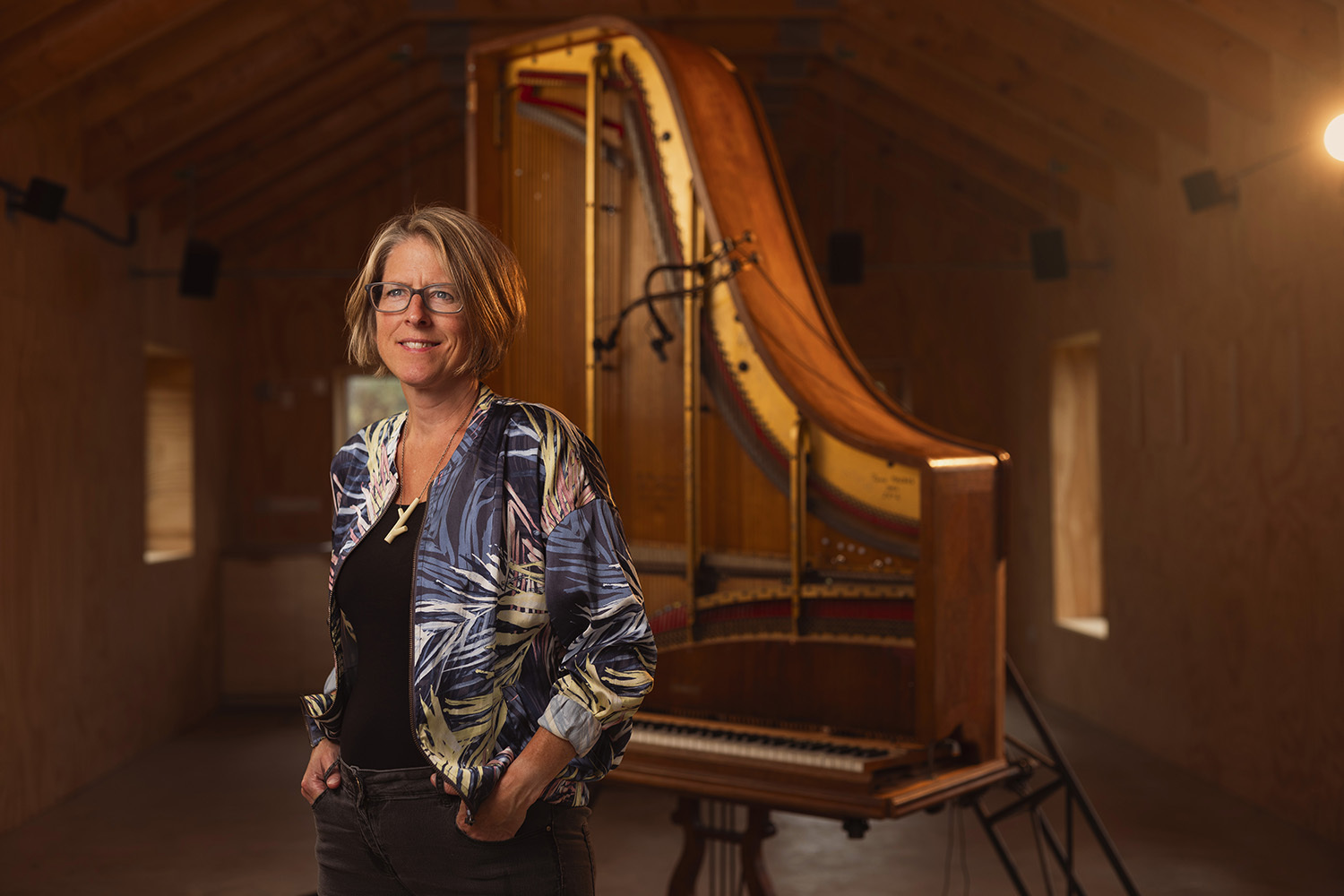 A woman standing proudly in front of a large, stringed musical instrument.