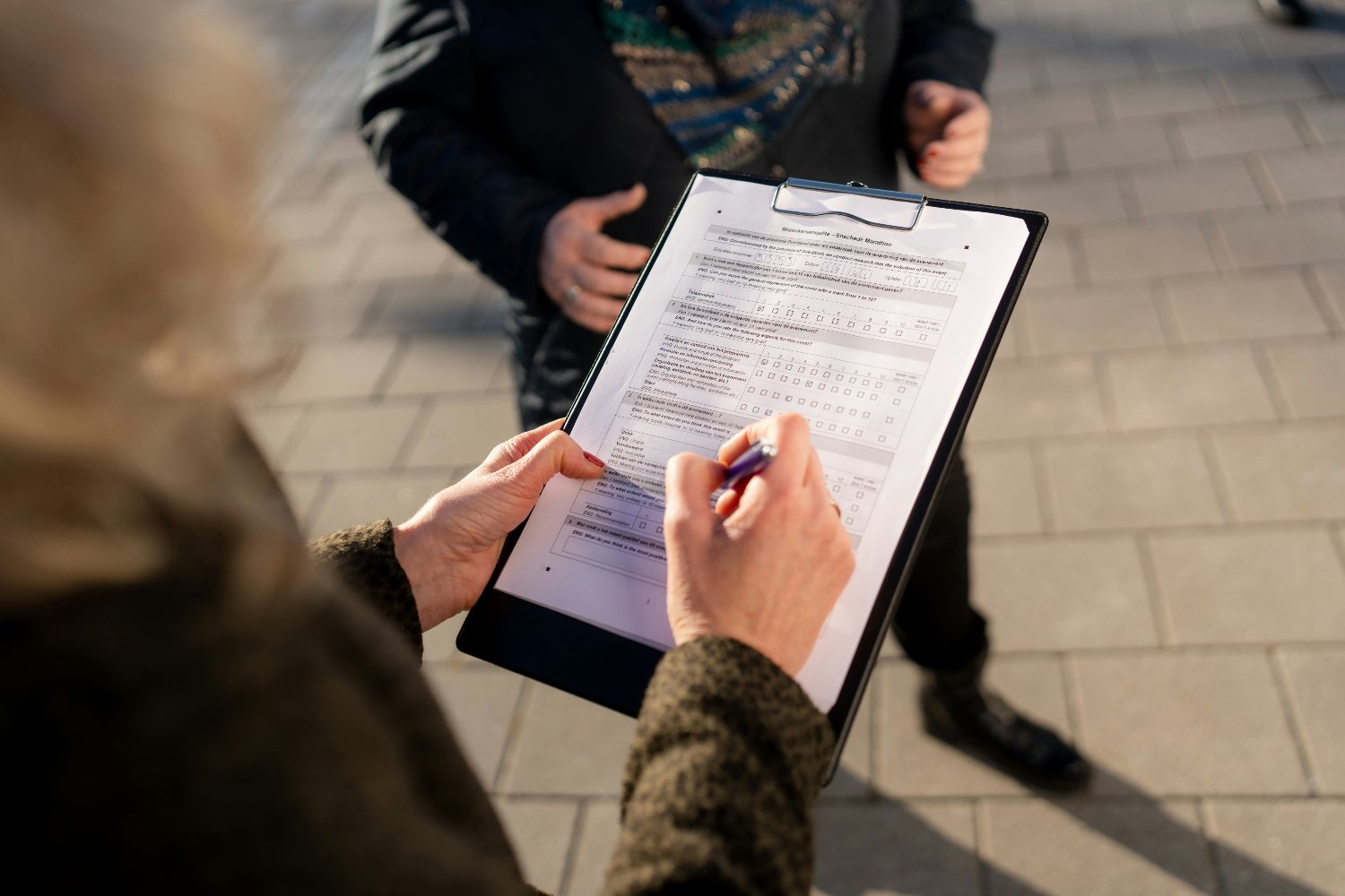 Woman with a clip board and paper completing a survey with a pen